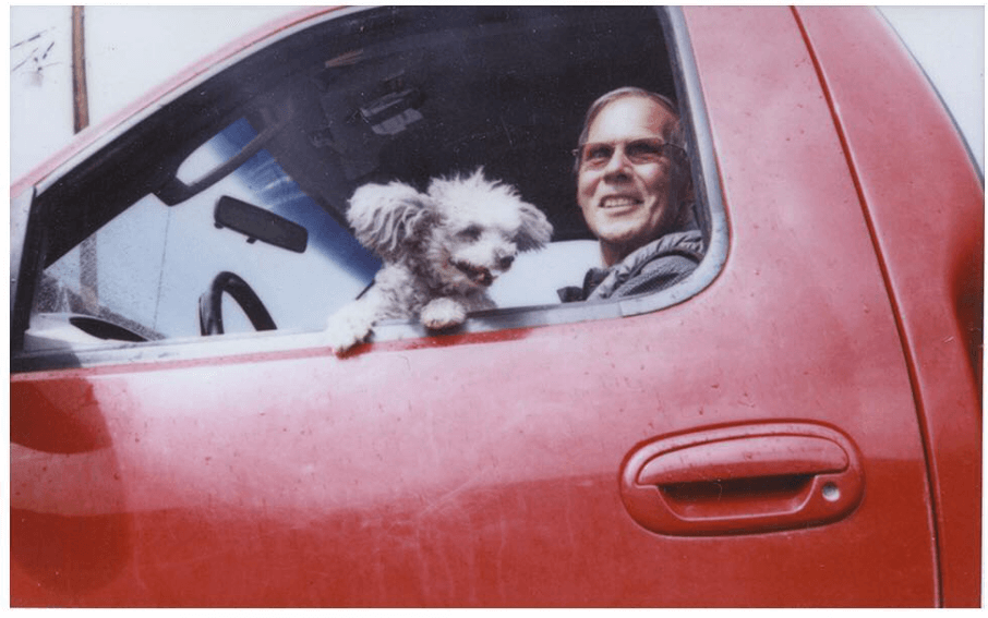 Man and doc in a red truck in the parking lot of a gas station in Dubois, Wyoming.